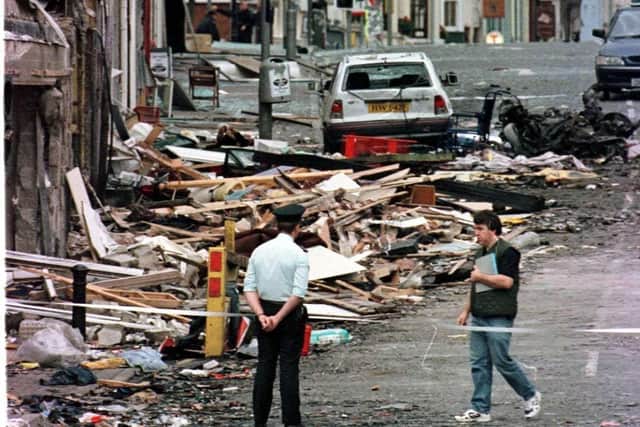 A Royal Ulster Constabulary officer looking at the damage caused by a bomb explosion in Market Street, Omagh in 1998.