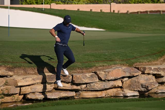Rory McIlroy of Northern Ireland jumps over rocks, to cross the water on the 18th hole during Day Two of the DP World Tour Championship on the Earth Course at Jumeirah Golf Estates on November 17, 2023 in Dubai, United Arab Emirates. (Photo by Ross Kinnaird/Getty Images)