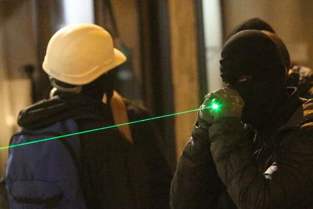 A masked protester holds a laser pointer