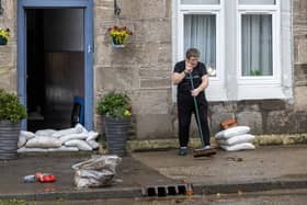A woman clears away mess left by floodwater in Dumbarton, West Dunbartonshire, as Scotland and northern parts of England are forecast to suffer extreme rainfall and flooding, whilst southern parts of the UK are set to bask in a late blast of summer over the weekend. The Met Office issued an amber weather warning for much of Scotland, and the Scottish Environmental Protection Agency (Sepa) warned against perceiving the situation as "normal autumn". Picture date: Saturday October 7, 2023.  Photo : Robert Perry/PA Wire
