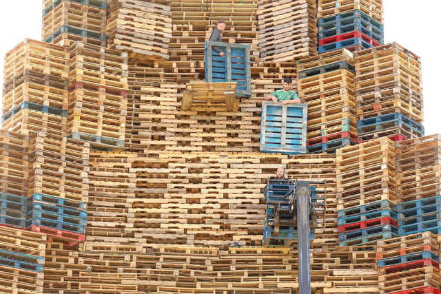 Bonfire builders move pallets to the top with the help of a forklift truck