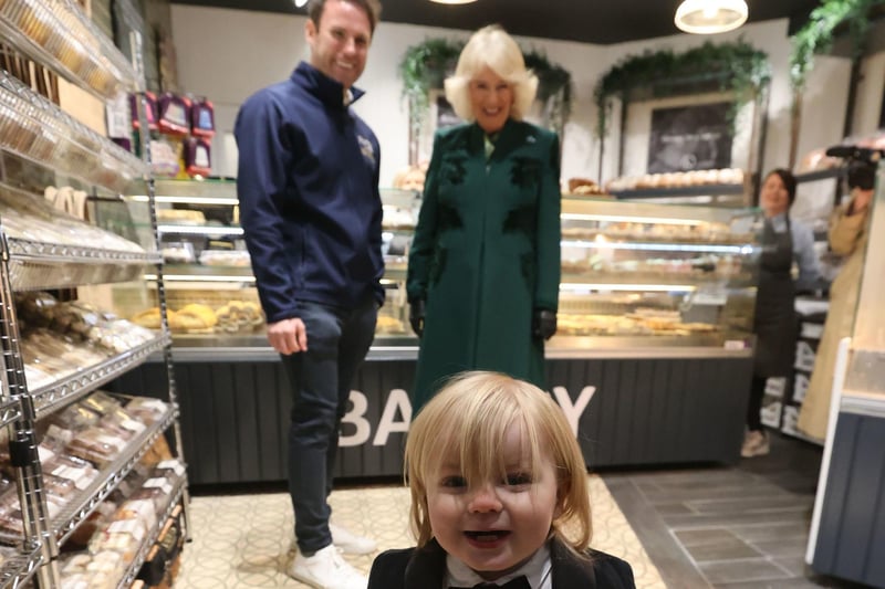 Queen Camilla meets the owner of Knotts Bakery, William Corrie with his son Fitz during a visit to Lisburn Road in Belfas