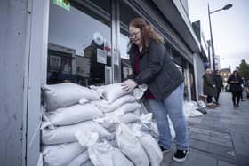 Marie Curie Downpatrick store manager Lisa Glackin stacks sand bags against the entrance to the store on Market Street in Downpatrick Photo: Gareth Fuller/PA Wire