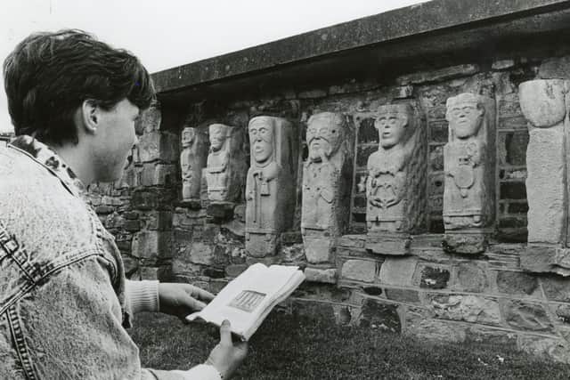 A STUDY IN STONE: A visitor to White Island on Fermanagh's Lower Lough Erne in October 1987, looks at the island's mysterious stone figures. Some say the figures are Christians, others think they are pagan. Those who think the figures are Christian say the figures represent, from left, a grotesque female figure as used in church gargoyles, a monk, an abbot of abbess, St Patrick of St Columba, Enna, son of King Leaghaire, offering a sacrifice and, finally, King Leaghaire. Picture: News Letter archives/Darryl Armitage