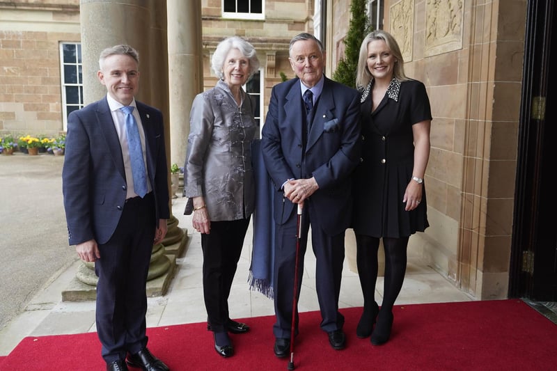 John de Chastelain and wife Mary Ann is welcomed by Laura McCorry of Hillsborough Castle (right) and Ryan Feeney (left) of Queen's University at a Gala dinner to recognise Mo Mowlam's contribution to the peace process and to mark the 25th anniversary of the Good Friday Agreement at Hillsborough Castle in Northern Ireland.
