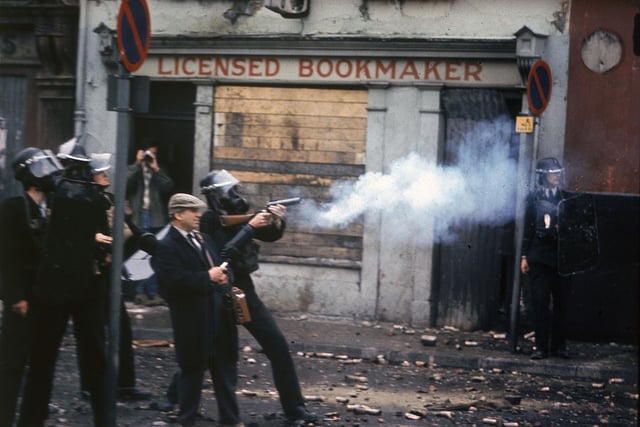 12th August 1969:  Police wearing gas masks fire cartridges of tear gas in front of a bookmakers during the Ulster riots in Londonderry, Northern Ireland.  (Photo by Hulton Archive/Getty Images)