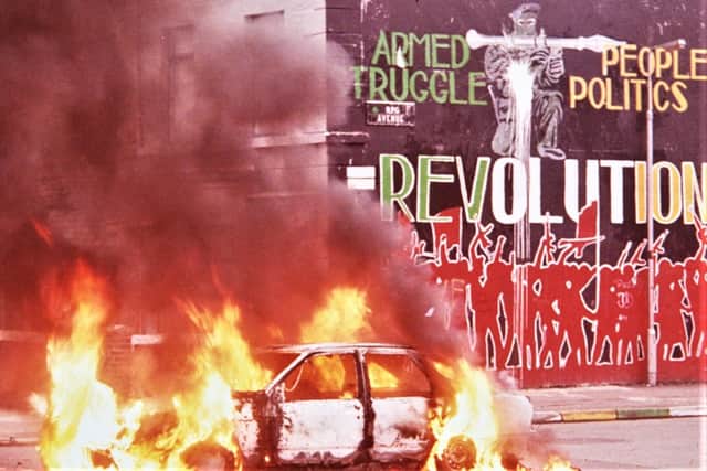 A masked man with a rocket launcher glares out from a mural glorifying republican paramilitarism on the lower Falls, west Belfast, July 1988, as a car burns nearby. Republicans murdered roughly 60% of the fatal victims of the Troubles.