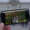 A person watches an announcement on a smart phone outside Buckingham Palace by the Princess of Wales, who has revealed she is undergoing chemotherapy treatment for cancer. She announced the news in a pre-recorded message that was broadcast on Friday evening