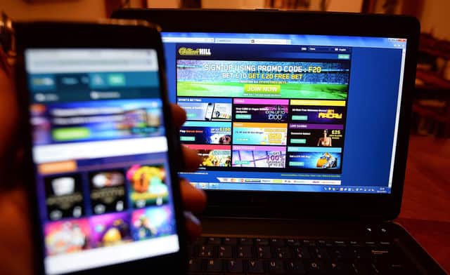 File photo of a smartphone user accessing the William Hill gambling website on their phone and a laptop. Photo credit: John Stillwell/PA Wire