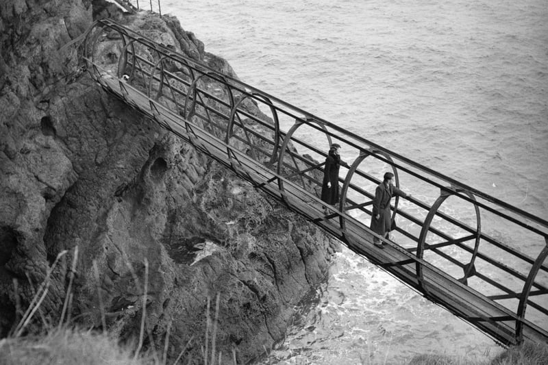 circa 1935:  Two people take in the view from a footbridge on the coast at Gobbins, County Antrim.  (Photo by Fox Photos/Getty Images)