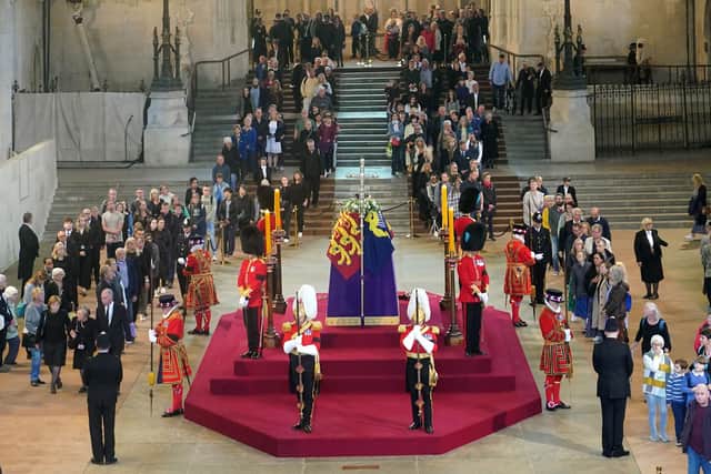 Members of the public file past the coffin of Queen Elizabeth II, draped in the Royal Standard with the Imperial State Crown and the Sovereign's orb and sceptre, lying in state on the catafalque in Westminster Hall, at the Palace of Westminster, London, ahead of her funeral on Monday.