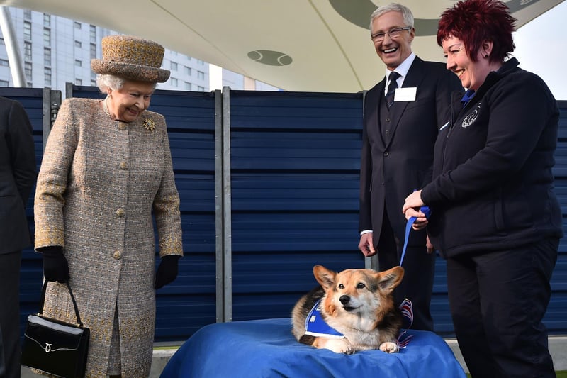 File photo dated 17/03/15 of Queen Elizabeth II looking at a Corgi as Paul O'Grady looks on during a visit to Battersea Dogs and Cats Home in London.