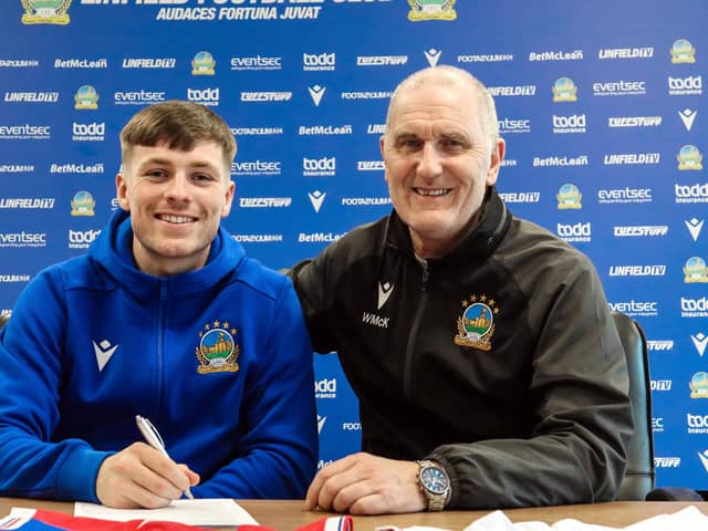 Linfield striker Chris McKee puts pen to paper on a new two-year contract at the National Stadium. He is pictured with chief scout Willie McKeown. PIC: Pacemaker