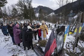 Priest Ivan Rybaruk prays with the family of fallen Ukrainian soldier Victor Ivanov at the cemetery during Christmas celebration in Kryvorivnia village, Ukraine, on Dec. 24. Ivanov was killed by Russian armed forces near Bakhmut. Journalists have died in the conflict too (AP Photo/Evgeniy Maloletka)
