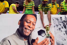 A Brazil fan holds a replica World Cup trophy over a picture of former player Pele ahead of the FIFA World Cup Group G match at the Lusail Stadium in Lusail, Qatar on Friday.