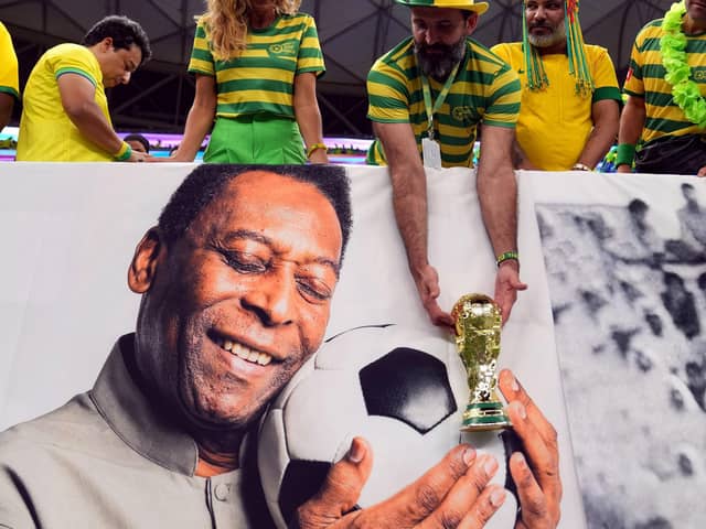 A Brazil fan holds a replica World Cup trophy over a picture of former player Pele ahead of the FIFA World Cup Group G match at the Lusail Stadium in Lusail, Qatar on Friday.
