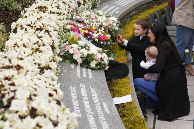 Bernadette Duffy (right) with son Daithi, aged 4, and daughter Saoirse, aged 4 months, lay flowers during a service to mark the 25th anniversary of the Omagh bomb
