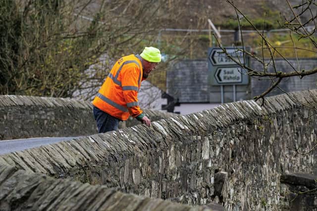 A man from M.T.L Fencing & Contracting looks on at a section of the Quoile bridge on the Killyleagh Road on the outskirts of Downpatrick where part of the bridge has came away from the road after heavy flooding in recent weeks. Picture date: Monday November 13, 2023. PA Photo. See PA story WEATHER Debi Ulster. Photo credit should read: Liam McBurney/PA Wire