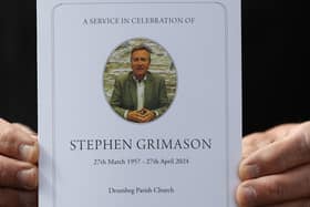 A mourner holds the order of service for the the funeral mass of former BBC Northern Ireland political editor and director of communications at Stormont, Stephen Grimason, at Drumbeg Parish Church in Dunmurry