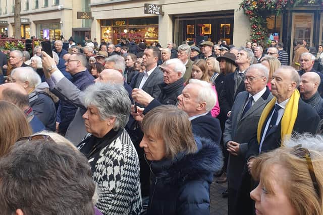 People gather outside Harrods Department Store, Hans Crescent, Knightsbridge, London SW1 as flowers are laid at the memorial plaque for the IRA bomb on Sunday December 17 2023, the 40th anniversary of the bomb, to honour the six people who were killed