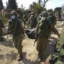 Israeli soldiers lcarry a body of a person killed in Hamas attack in kibbutz Kfar Azza on Tuesday, Oct. 10, 2023. Hamas militants overran Kfar Azza on Saturday, where many Israelis were killed and taken captive. (AP Photo/Erik Marmor)