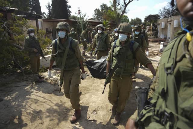 Israeli soldiers lcarry a body of a person killed in Hamas attack in kibbutz Kfar Azza on Tuesday, Oct. 10, 2023. Hamas militants overran Kfar Azza on Saturday, where many Israelis were killed and taken captive. (AP Photo/Erik Marmor)