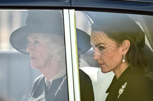 Camilla, Queen Consort (L) and Catherine, Princess of Wales are driven behind the coffin of Queen Elizabeth II, adorned with a Royal Standard and the Imperial State Crown and pulled by a Gun Carriage of The King's Troop Royal Horse Artillery, during a procession from Buckingham Palace to the Palace of Westminster, in London on September 14, 2022.