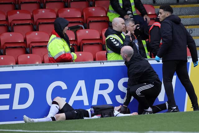 Glentoran's Bobby Burns receives treatment after colliding with an advertising board at Seaview on Saturday. (Photo by David Maginnis/Pacemaker Press)