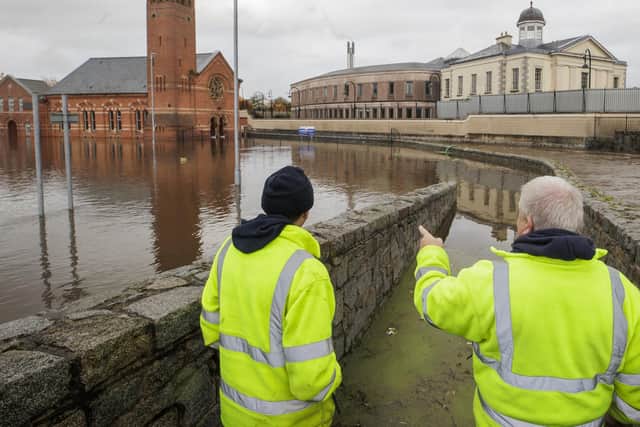 DFI workers look at the flooded water in a car park beside Riverside Reformed Presbyterian Church (left) and Newry Courthouse (right) in Newry Town, Co Down. 
Photo credit should read: Liam McBurney/PA Wire