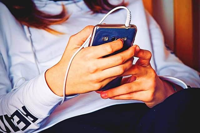A youth holding a mobile phone; in Ireland, possession of material capable of 'inciting hate' on private devices like phones will soon be a jailable offence
