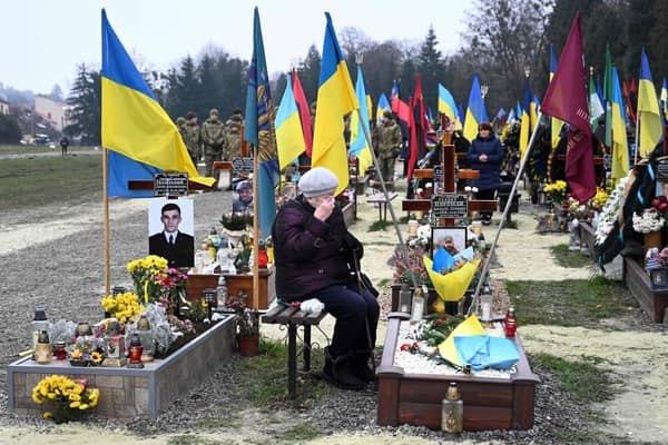 An elderly woman grieves next to the grave of a Ukrainian soldier in the city of Lviv
