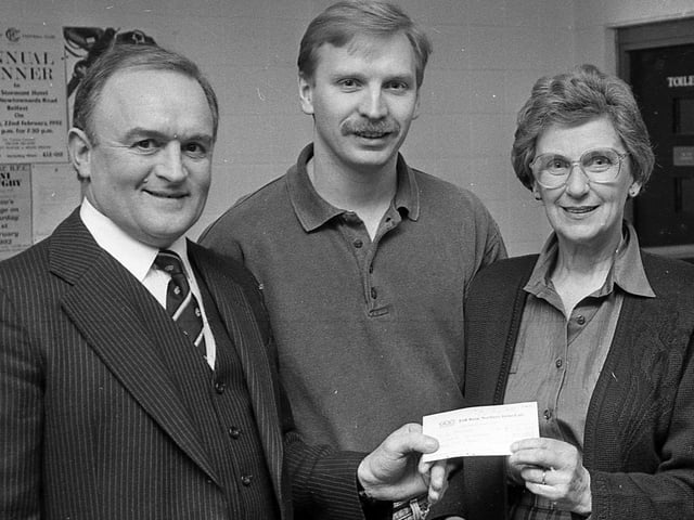 Billy Sampson gives NI Hospice treasurer Muriel Brotherston a cheque for £1,200 in February 1992. The money was raised by the Maureen Sampson Memorial Appeal Fund, supported by Cooke Rugby Club whose social convenor Tommy Napier, centre, attended the presentation. Picture: News Letter archives