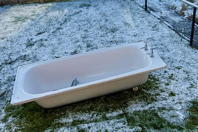 The ancient bath sits desolately on the snow-covered lawn