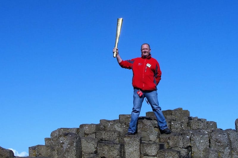 Bushmills man Neville McConachie with Olympic torch at the Giant's Causeway