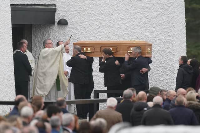 Priest Fr John Joe Duffy sprinkles holy water on the coffin of Martin McGill, 49,as it arrives at St Michael's Church, Creeslough, for his funeral mass.