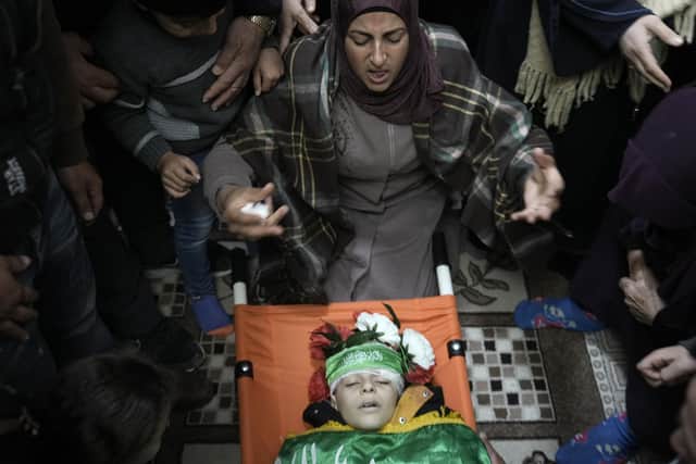 The mother of Amr al-Najjar, 11, draped in the Hamas flag, weeps during his funeral in the West Bank village of Burin, near Nablus, Tuesday, March 5, 2024.Photo: (AP Photo/Majdi Mohammed)