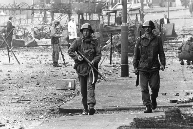 16th August 1969:  British soldiers on patrol beside barbed wire defences at the junction of Percy Street and Falls Road in Belfast during unrest in Northern Ireland.  (Photo by James Jackson/Evening Standard/Getty Images)