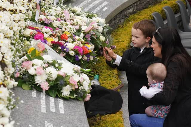 Bernadette Duffy (right) with son Daithi, aged 4, and daughter Saoirse, aged 4 months, lay flowers during a service to mark the 25th anniversary of the bombing that devastated Omagh in 1998