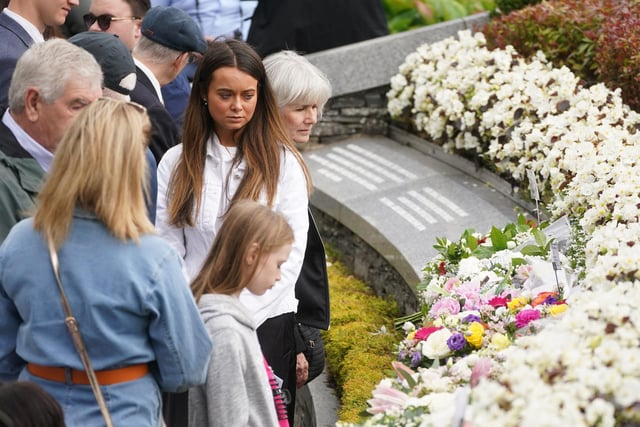 People gather at the monument in Omagh following a service to mark the 25th anniversary of the bombing that devastated the town in 1998