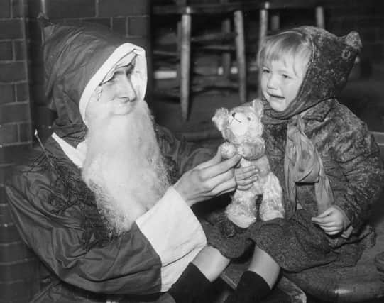 A child visiting Santa in Hoxton is unhappy despite her new teddy bear.  (Photo by Parker/Fox Photos/Getty Images)