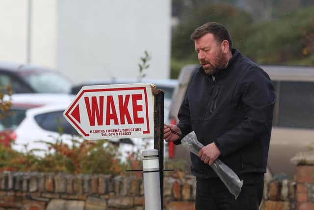 Funeral director Leo Harkins erects a sign for the wake for Martin McGill, 49, who died in the explosion at Applegreen service station in the village of Creeslough in Co Donegal on Friday, where ten people have now been confirmed dead.