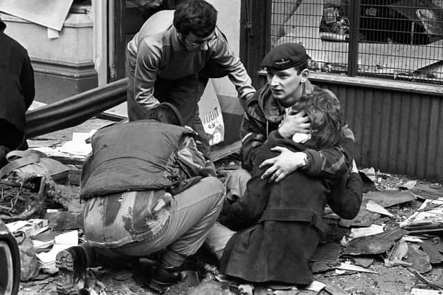 A British paratrooper takes a young girl in his arms to comfort her after she was hurt in a 1972 bomb blast in Donegal Street, Belfast. Photo: Derek Brind/PA Archive