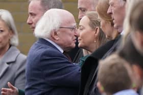 Irish President Michael D. Higgins hugs Tracey O'Flaherty, the widow of James O'Flaherty as he arrives for the funeral mass for Mr O'Flaherty at St Mary's Church, Derrybeg.