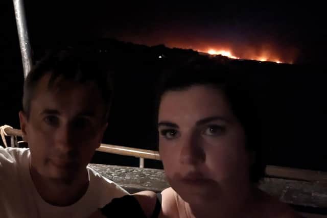 Photo by Conor Cullen of himself and his wife Danielle with wildfires on the Greek island of Rhodes behind them