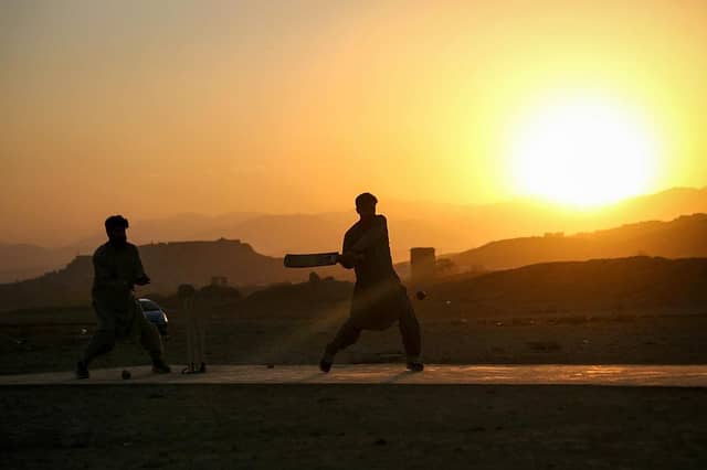 Afghan boys play cricket at a field on the outskirts of Ghazni on October 23, 2025; sport is banned for females in Afghanistan, and the women's cricket team have largely gone into exile (photo via Getty Images)