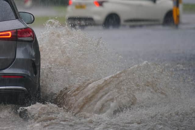 Cars drive through a flooded road after heavy rain in Speke, Liverpool on Saturday. Photo: Peter Byrne/PA Wire