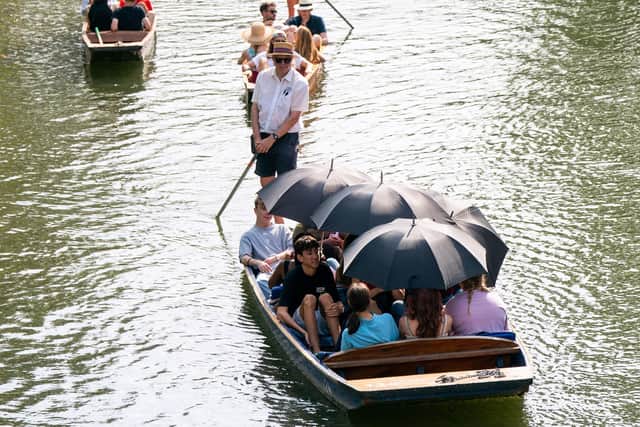 People use umbrellas to shelter from the sun whilst taking a punt tour along the River Cam in Cambridge, which was the hottest place in the UK on Sunday. Joe Giddens/PA Wire