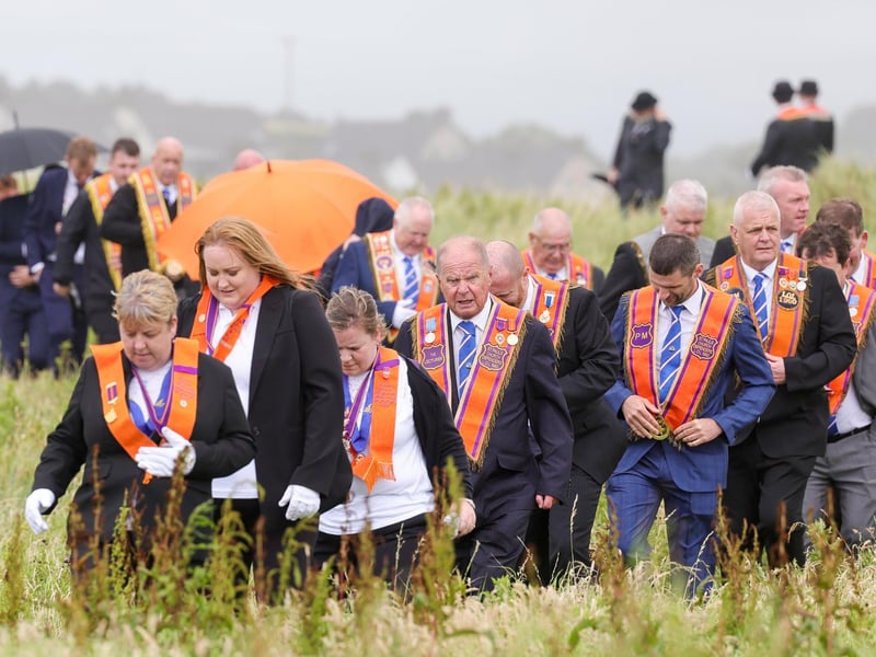 Orange men and women make their way through the dunes to the beach