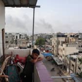 A boy stands on a balcony with a view of billowing smoke due to renewed Israeli strikes in Rafah city in the southern Gaza Strip on May 28, 2024, amid the ongoing conflict between Israel and the Palestinian Hamas militant group (Photo by EYAD BABA/AFP via Getty Images)