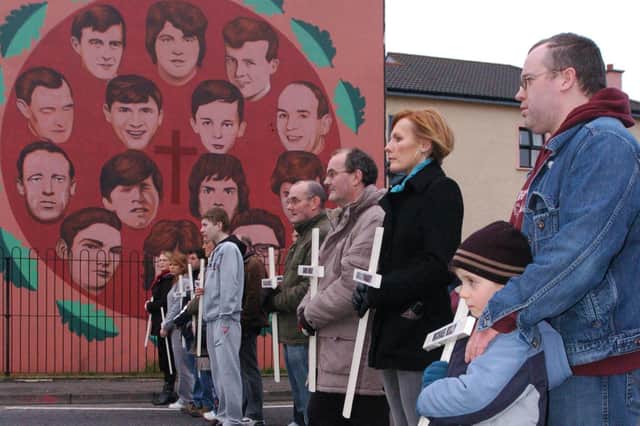 Relatives carrying crosses pause at the mural in the Bogside remembering the people killed on Bloody Sunday. (3001PG76)